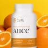 Bottle of AHCC in front of a group of oranges.